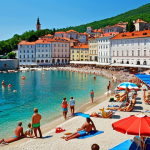 **A picturesque Slovenian coastal town like Piran during summer, with sunny weather. Capture the vibrant colors of the buildings, the clear blue Adriatic Sea, and people enjoying the beach. Include details like colorful umbrellas, sunbathers with sunscreen, and light, summery clothing. The overall feeling should be one of warmth and relaxation.**